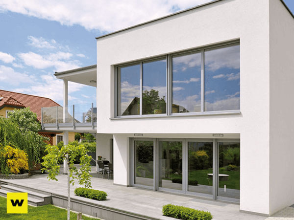 Modernes Einfamilienhaus mit großen Fenstern, Garten und Terrasse bei sonnigem Wetter.