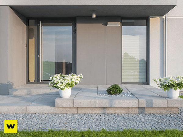 Moderner Hauseingang mit grauen Fliesen, weißen Blumentöpfen und minimalistischer Deko.